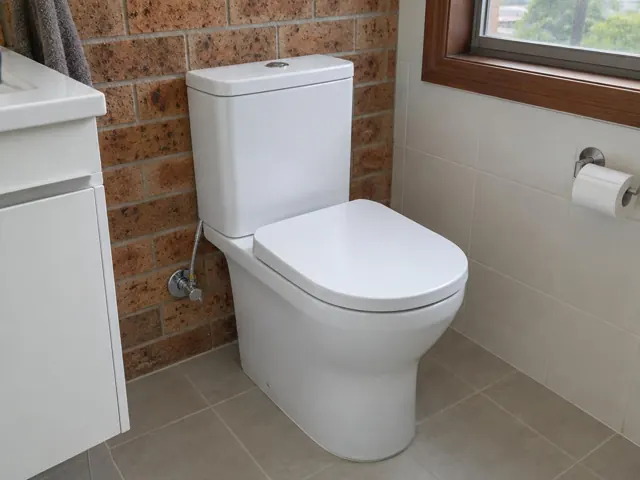 White toilet in a tiled bathroom with brick feature wall and window in Wangi Wangi